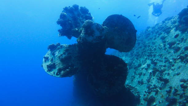 istock Scuba diving at ship wreck propeller in blue deep water, man diver on the background 1250523727
