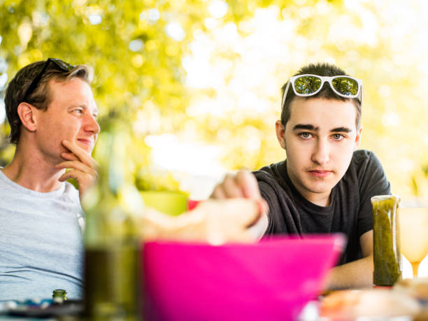 Hands of man drinking beer and making hot dogs for friends at beach party