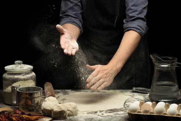 istock Chef hands are clapping wheat flour under rolled dough. Black background 1250524956