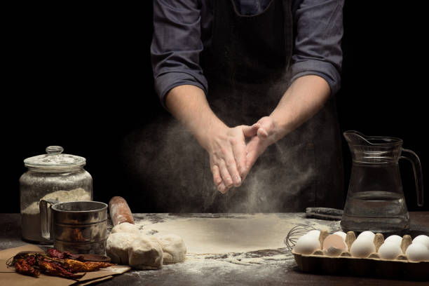 istock Chef hands are working with wheat flour to make a dough.  black background 1250525617