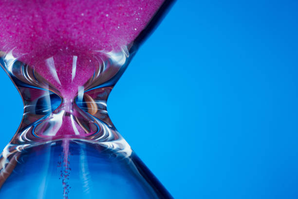 istock Pink sand hourglass on blue background 1250526111