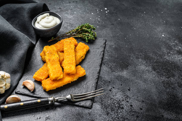 istock Oven baked crumbed fish sticks made from white fish.  Black background. Top view. Copy space 1250527479