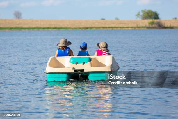 Rear View Of Three Children In Paddle Boat On Small Lake Stock Photo - Download Image Now