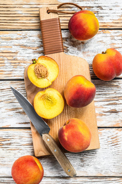 istock Fresh Peaches, organic fruit on the chopping Board. White wooden background. Top view 1250528986
