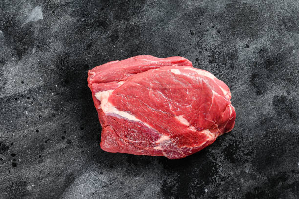 istock Raw Round beef cut. Black background. Top view 1250529023