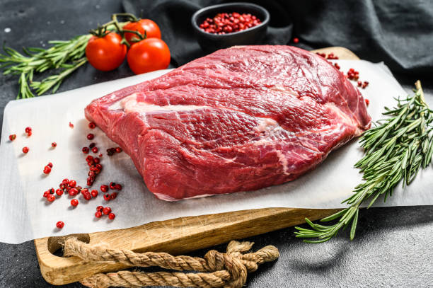 istock Raw Round beef cut on a cutting board. Black background. Top view 1250530075