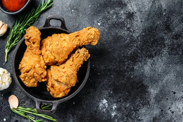 Photo of Spicy Deep Fried Breaded Chicken drumsticks. Black background. Top view. Copy space