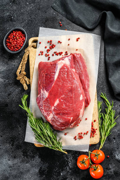 istock Raw Round beef cut on a cutting board. Black background. Top view 1250531245