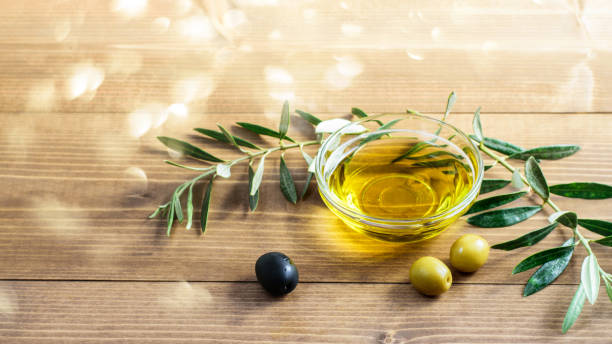 olive oil in glass bowl, olives and brnches of olive tree on the wooden table. - olive oil pouring antioxidant liquid imagens e fotografias de stock