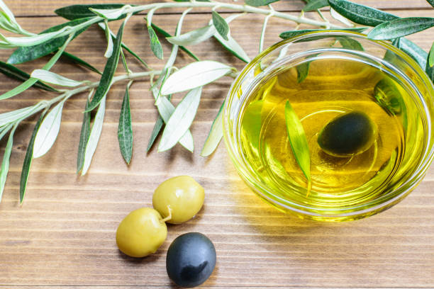 olives and fresh olive oil in the glass bowl, branches of olive tree on the wooden background. - olive oil pouring antioxidant liquid imagens e fotografias de stock