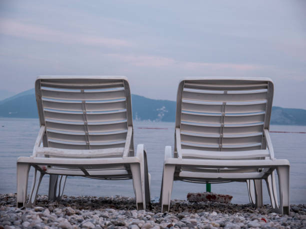 istock Two empty plastic chaise lounge on sea side at the end of season side view 1250536541