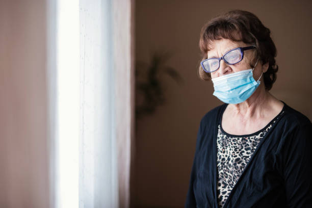 istock Lonely old woman looking through the window 1250538954
