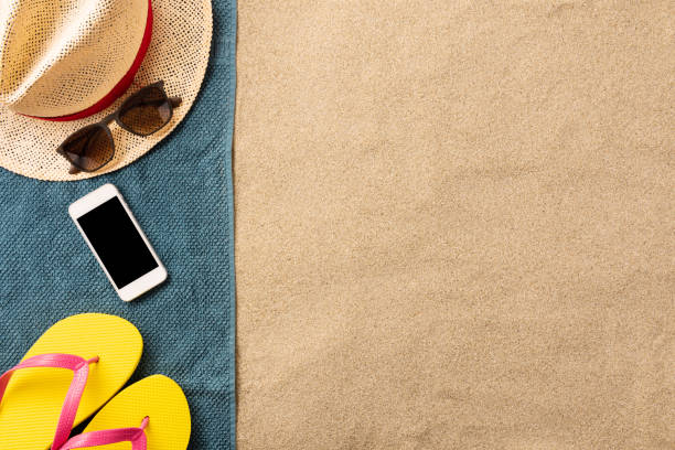 istock Summer vacation composition. Flip flops, and smartphone on sand background. Travel vacation concept. Summer background. Border composition made of towel 1250539683