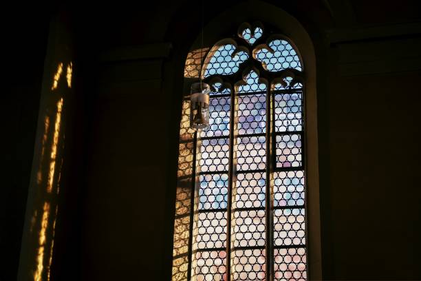 istock Beautiful window and a lamp in the german catholic church. Light and shadow 1250542521