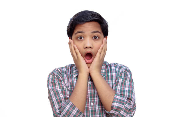 istock A school boy giving a shocking expression with a hand on a white background 1250544037