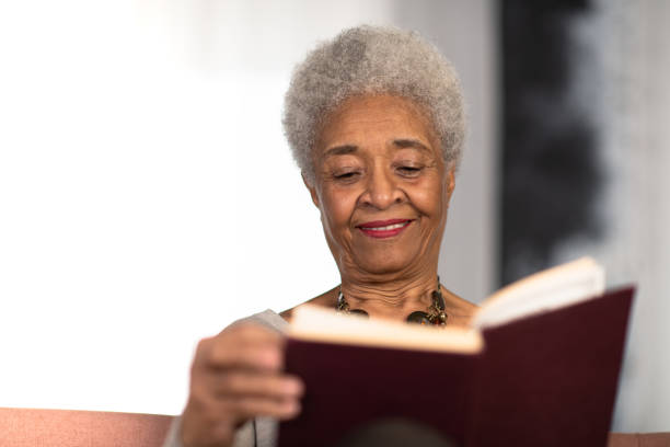 istock Senior woman reading happily at home 1250547078
