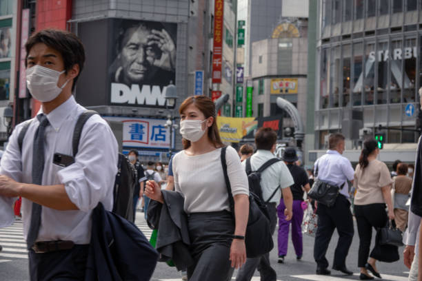 Crowd of people with face masks walking in shibuya crossing Shibuya, Tokyo, Japan - June 10, 2020: Crowd of people with face masks walking in the famous tourist place shibuya crossing, after the state of emergency expires, rush hour tokyo crowds on the famous shibuya crossing japan stock pictures, royalty-free photos & images