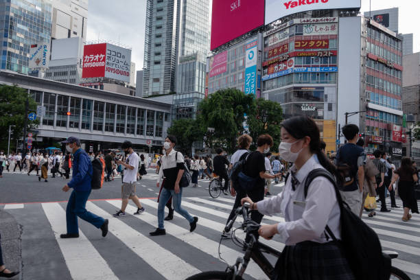 Crowd of people with face masks walking in shibuya crossing Shibuya, Tokyo, Japan - June 10, 2020: Crowd of people with face masks walking in the famous tourist place shibuya crossing, after the state of emergency expires, rush hour tokyo crowds on the famous shibuya crossing japan stock pictures, royalty-free photos & images