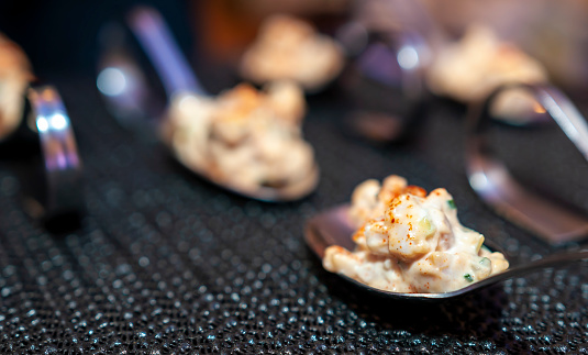 Small portions of dessert treats served on spoon-like receptacles; for self-service in a social gathering situation. A catering concept. Image taken under artificial lighting.
