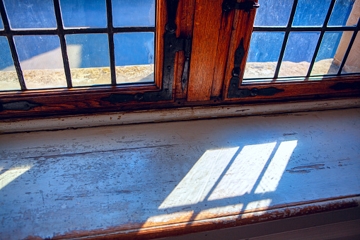 Old wooden cabin framed window looking out into green pasture. Vintage, rustic wood theme.