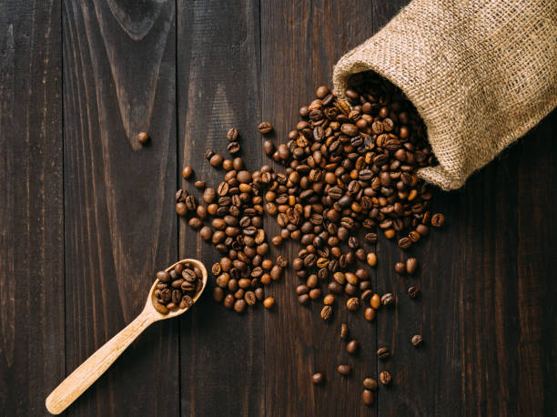 istock Spilling coffee beans on dark wooden table flat lay 1250558275