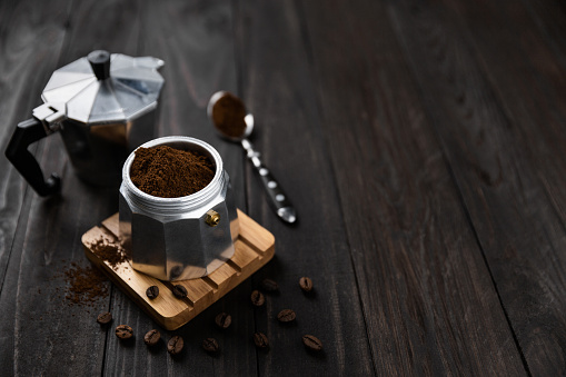 Isometric view of moka coffee maker on dark rustic kitchen table with copy space