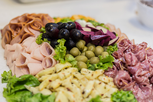 Cutting board with olives, sliced ​​ham, seasoned cheese and lettuce.