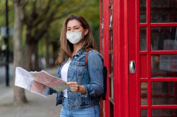 touristische sehenswürdigkeiten in london während des covid-19-ausbruchs mit einer gesichtsmaske, während sie eine karte halten - pay phone telephone people women stock-fotos und bilder