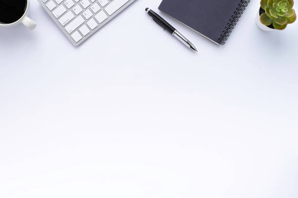 istock Top view above of white office desk table with keyboard, notebook and coffee cup with equipment other office supplies. Business and finance concept. Flat lay with blank copy space. 1250560750