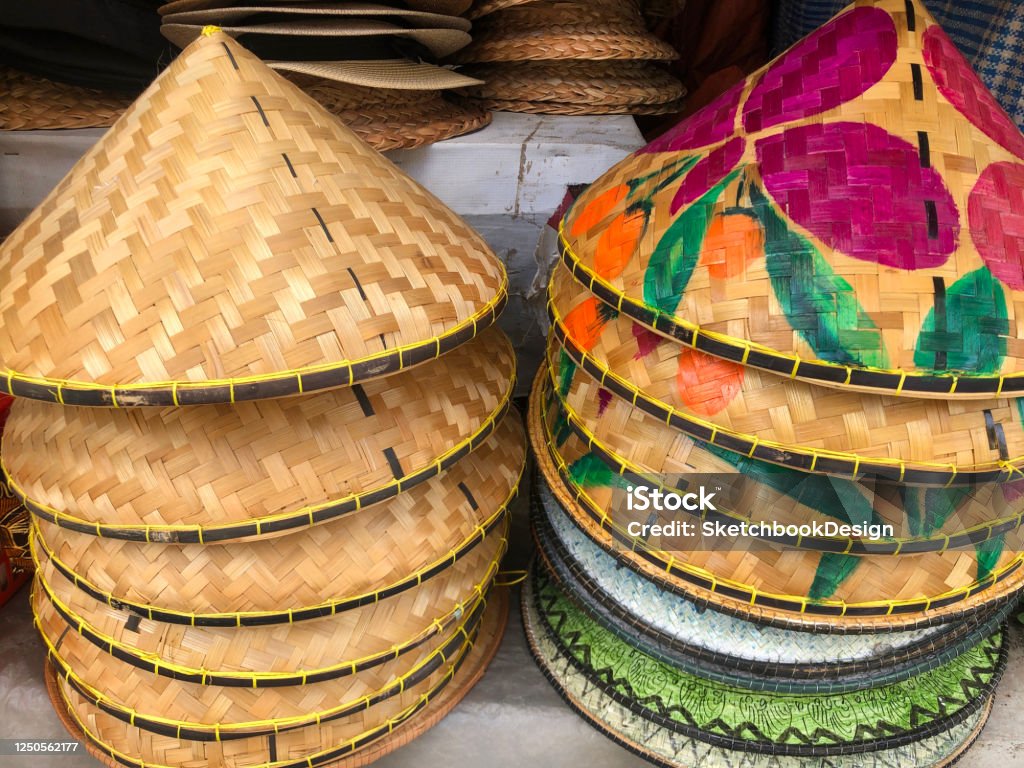 Asian rice field worker coolie hats being sold in a market in Ubud, Bali, Indonesia Hand-painted, woven ratan Asian coolie hats used by rice field workers. They are being sold in a market in Ubud, Bali, Indonesia, Southeast Asia. Agricultural Field Stock Photo