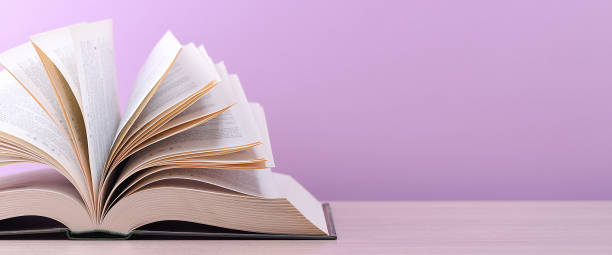 istock The book is open, lying on the table, sheets fanned out on a pink background. 1250568714