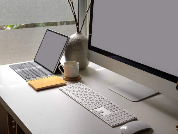 istock Office desk with blank screen tablet, computer device, coffee cup, supplies and decorations beside window 1250571345
