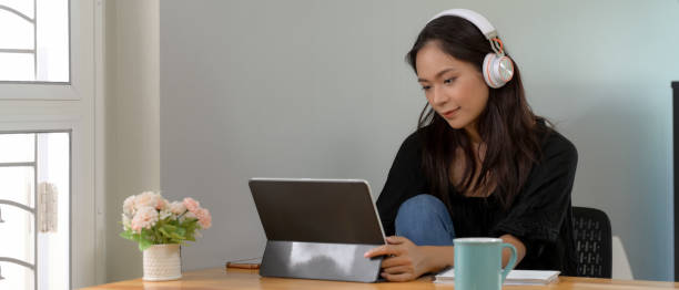 istock Female professor online teaching with digital tablet and notebook on wooden worktable in living room 1250571383