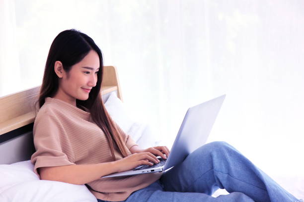 istock Asian young beautiful  woman sitting on bed using laptop work from home 1250571772