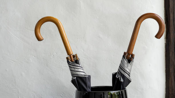 istock 2 black umbrellas in a large vase beside a white wall 1250576547