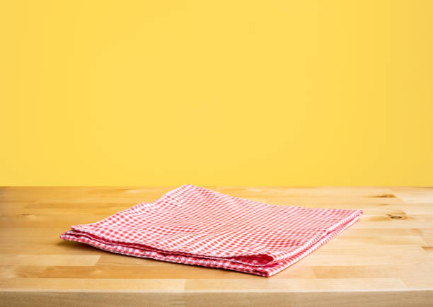 istock Red fabric,cloth on wood table top on yellow wall background 1250576709