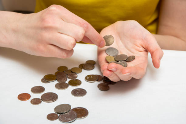 istock Saving money, a hand puts coins in another hand, on a light table are coins of different countries, close-up 1250580302