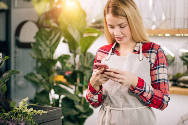 istock smiling lady florist with mobile phone at work 1250582510