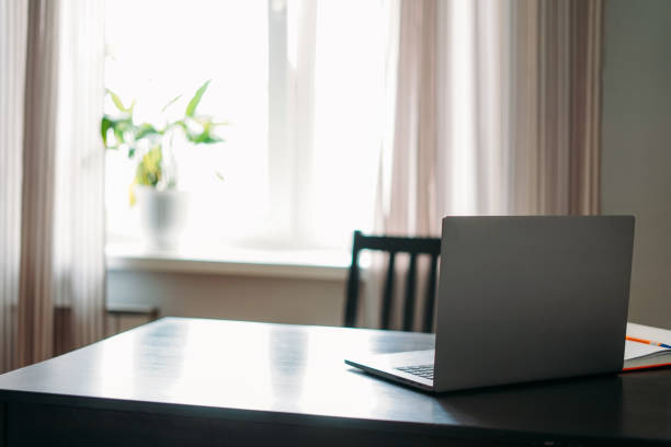 istock Opened laptop notebook on black table with mobile phone and notes against window at the home 1250586450