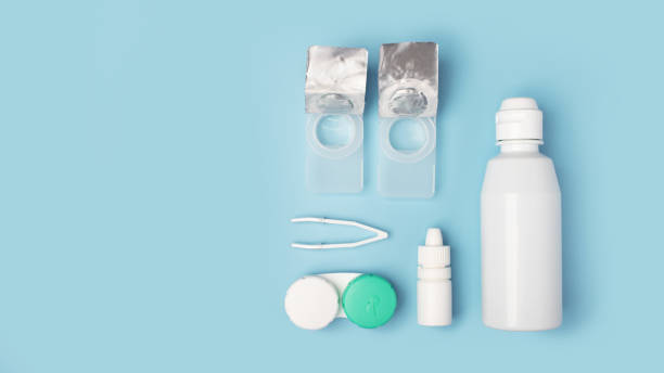 istock Contact lenses set with saline in bottle, tweezers, eye drops, plastic case with solution on blue background with copy space 1250590545
