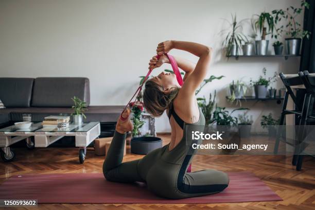 Young Woman Doing Yoga On The Floor In Living Room Stock Photo - Download Image Now - Flexibility, Strap, Yoga