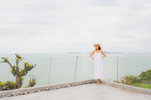 Portriat beautiful young asian woman happy smile around balcony with sea view background