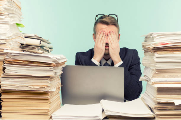Close-up image of a stressful businessman tired from his work on the foreground Close-up image of a stressful businessman tired from his work on the foreground - image bureaucracy stock pictures, royalty-free photos & images