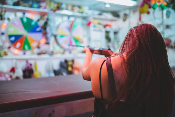 Brunette girl shooting for a prize at county fair at night.