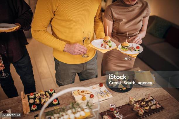 Business Colleagues Sampling Savory Dishes At Corporate Office Party Stock Photo - Download Image Now
