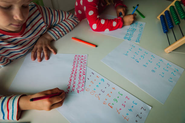istock boy and girl writing numbers, kids doing homework 1250601294