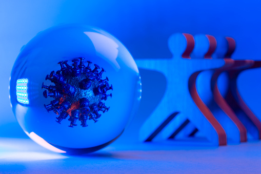 Mockup of virus in a glass sphere and wooden figures on blue background.