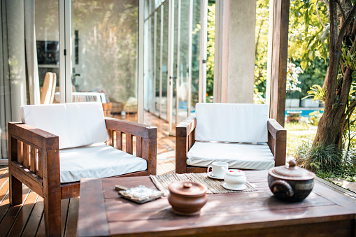Two outdoor chairs and table on wooden deck of modern Buenos Aires home in morning sunlight.
