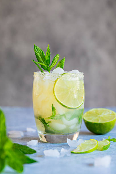 Mojito fresh drink with mint leaves and lime A fresh Mojito drink with mint leaves and lime and crushed ice. On a gray background. mojito stock pictures, royalty-free photos & images