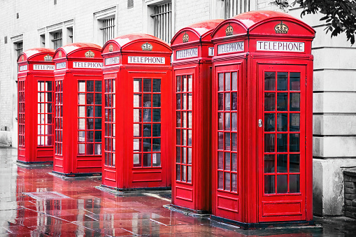 Traditional British red phone boxes in a row in Covent Garden, London. Colour removed from background to make the red stand out.